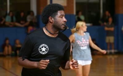 Students playing intramural sport in gym with referee.